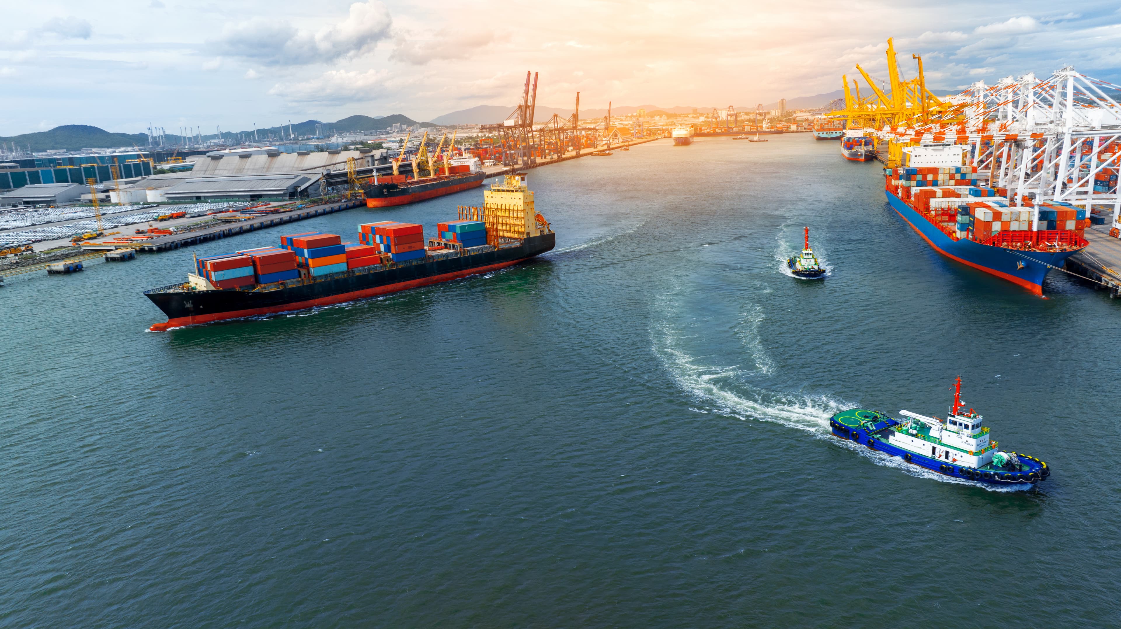 Container cargo ship and tug boats at a busy harbor terminal